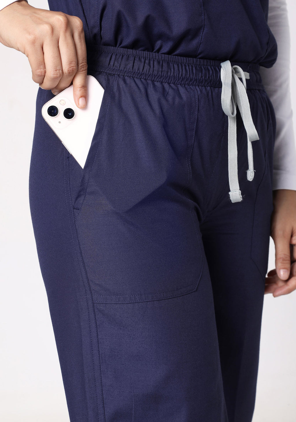 Close-up showing the deep, functional pocket of the Knyamed scrub pants easily holding a smartphone, with the drawstring waistband visible.